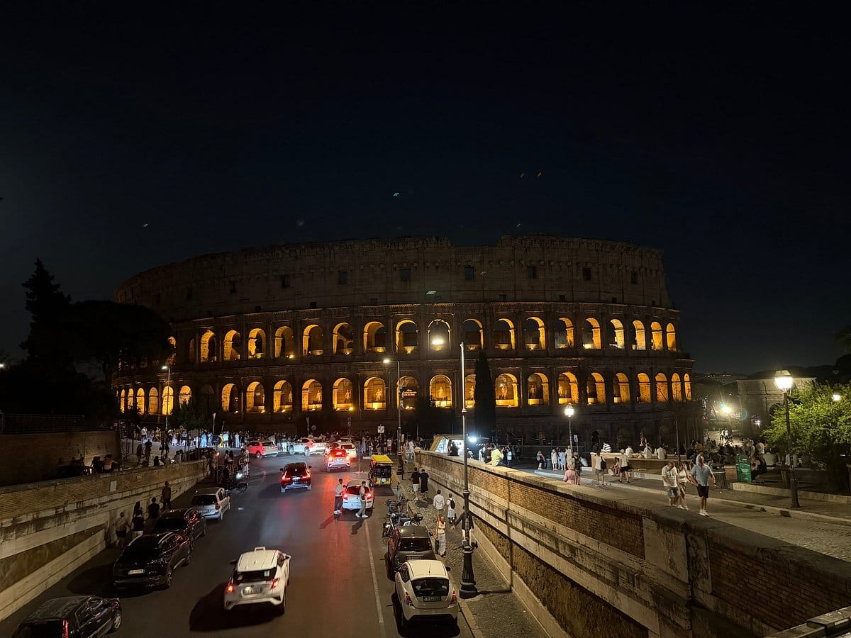 The Colosseum illuminated at night, seen from the street below
