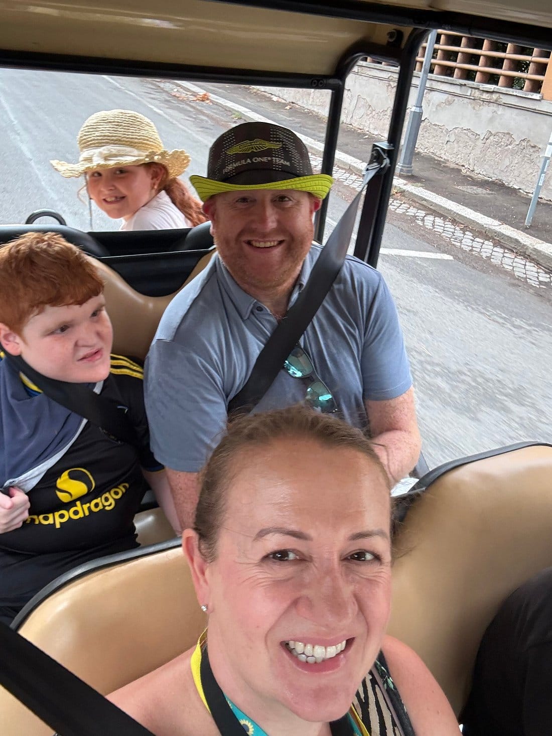 A family of four smiling together in the back of the golf cart during their tour